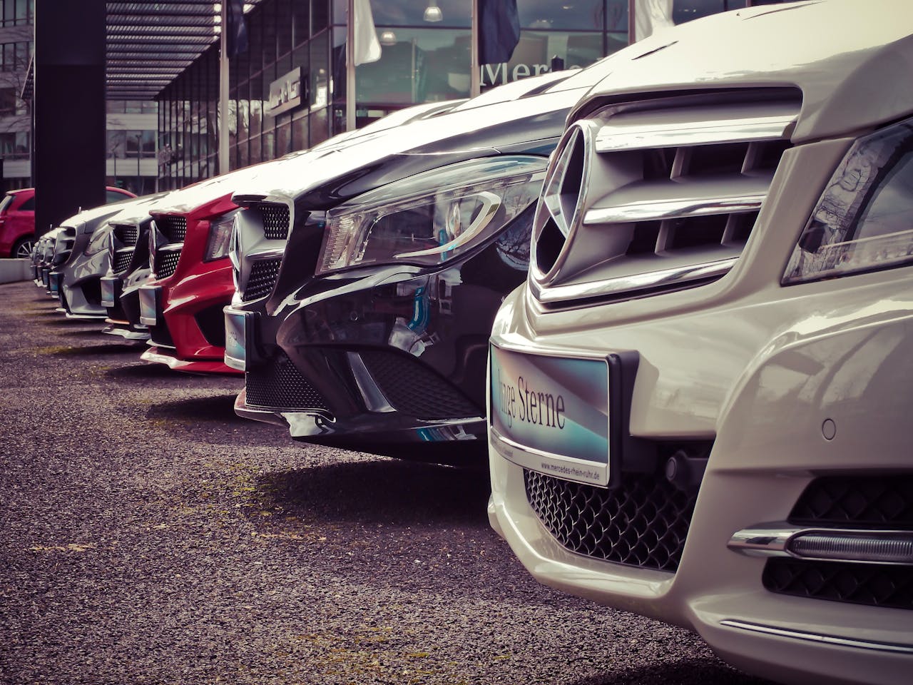 services-02 Luxury cars lined up at an outdoor dealership, showcasing sleek designs.